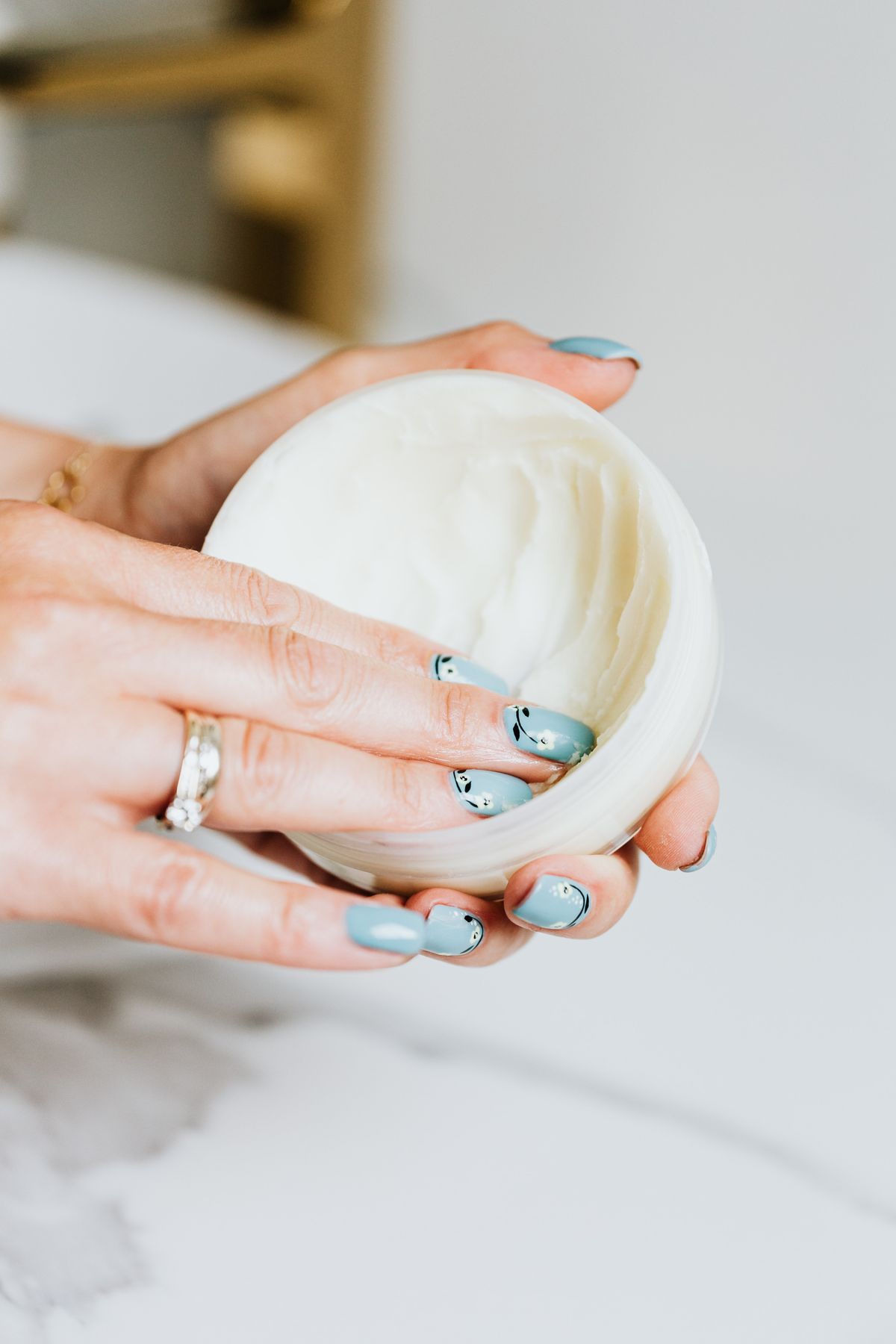 Hands holding a white container of cream