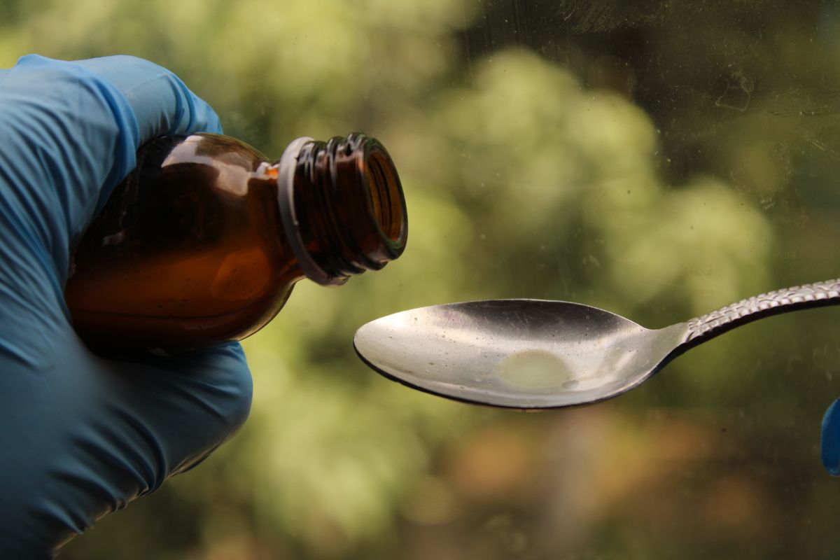 Liquid medicine from a brown bottle poured onto a spoon