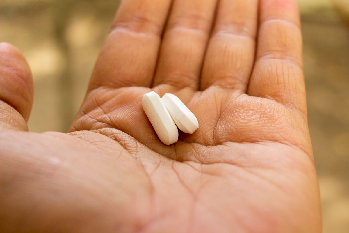 Two white tablets in an open hand