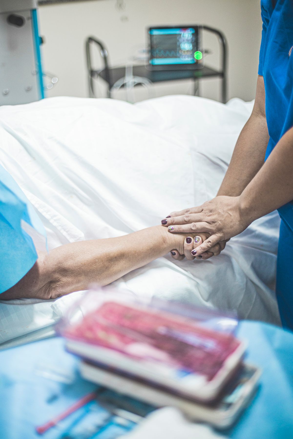 A nurse holding a patient's hand beside a hospital bed